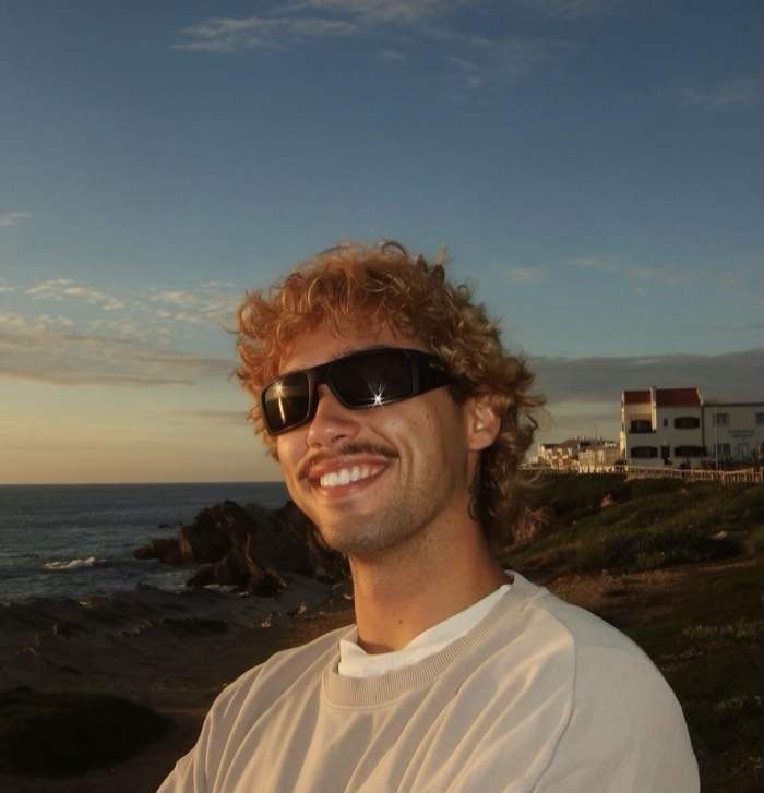 Lourenço Grandela smiling on the cliffs at sunset, the sea behind him.