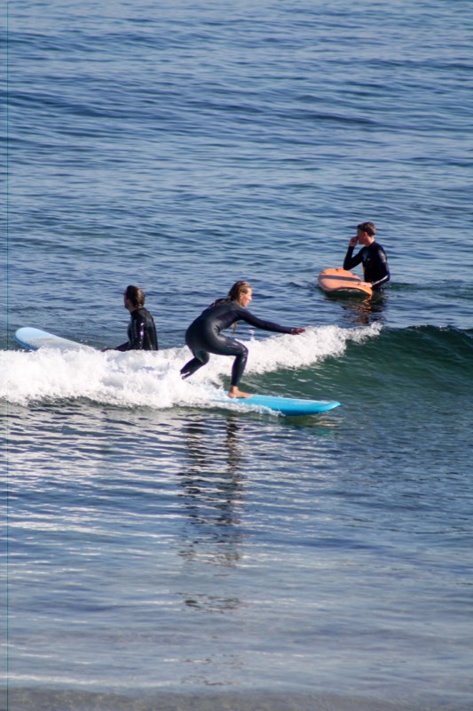 A student riding their first wave on a blue softboard