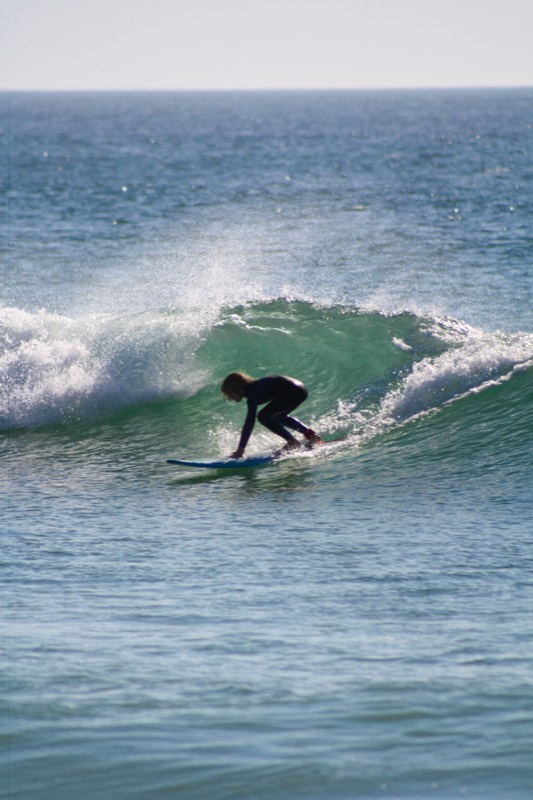 A young surfer riding an early wave in soft light