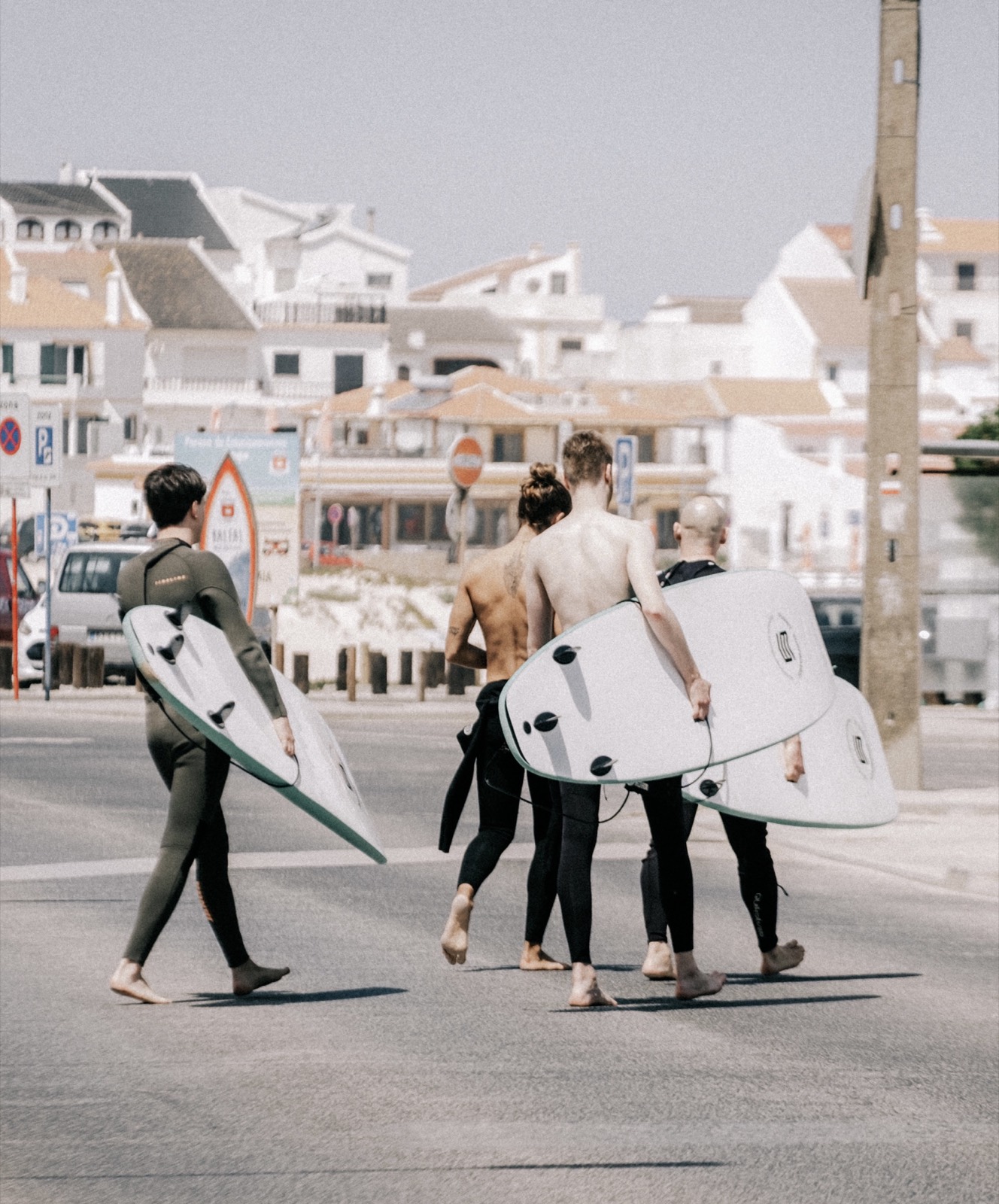 Surfers walking with boards between the white houses of Baleal village