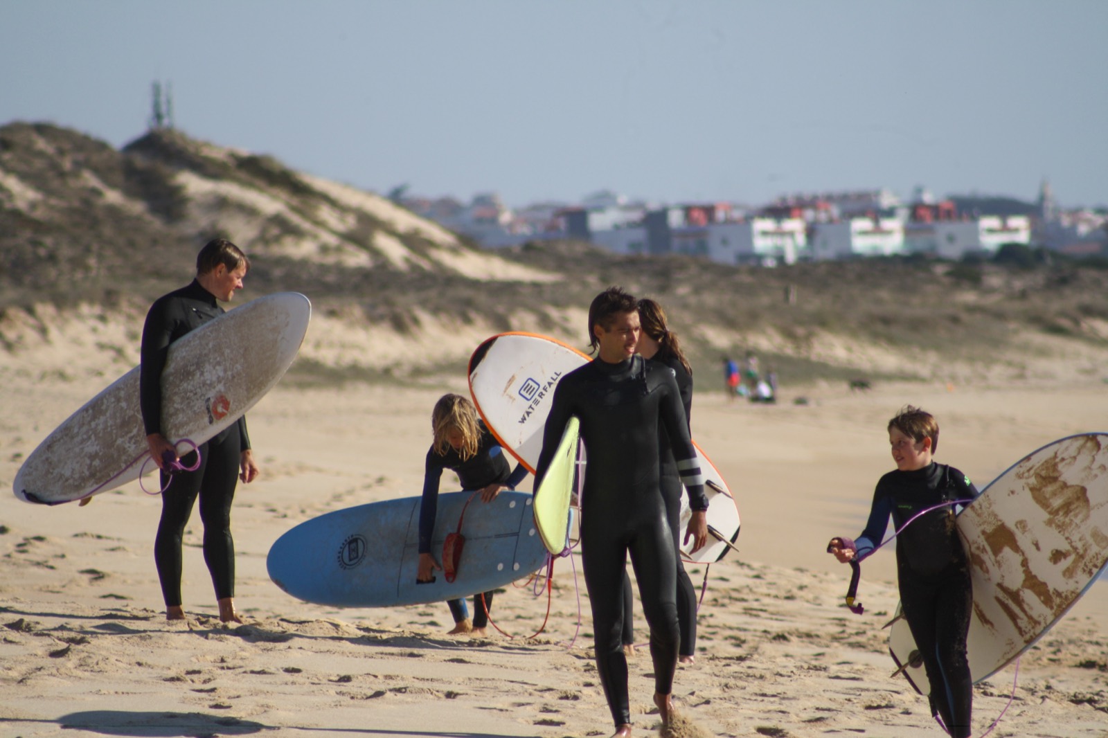 Surfers walking along the dunes of Praia do Baleal with boards under their arms
