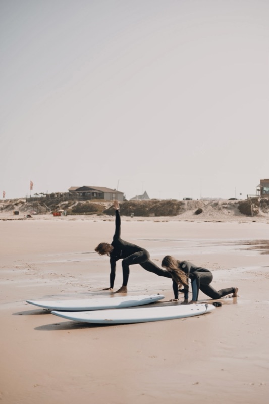 Two surfers stretching on the sand beside their boards before paddling out