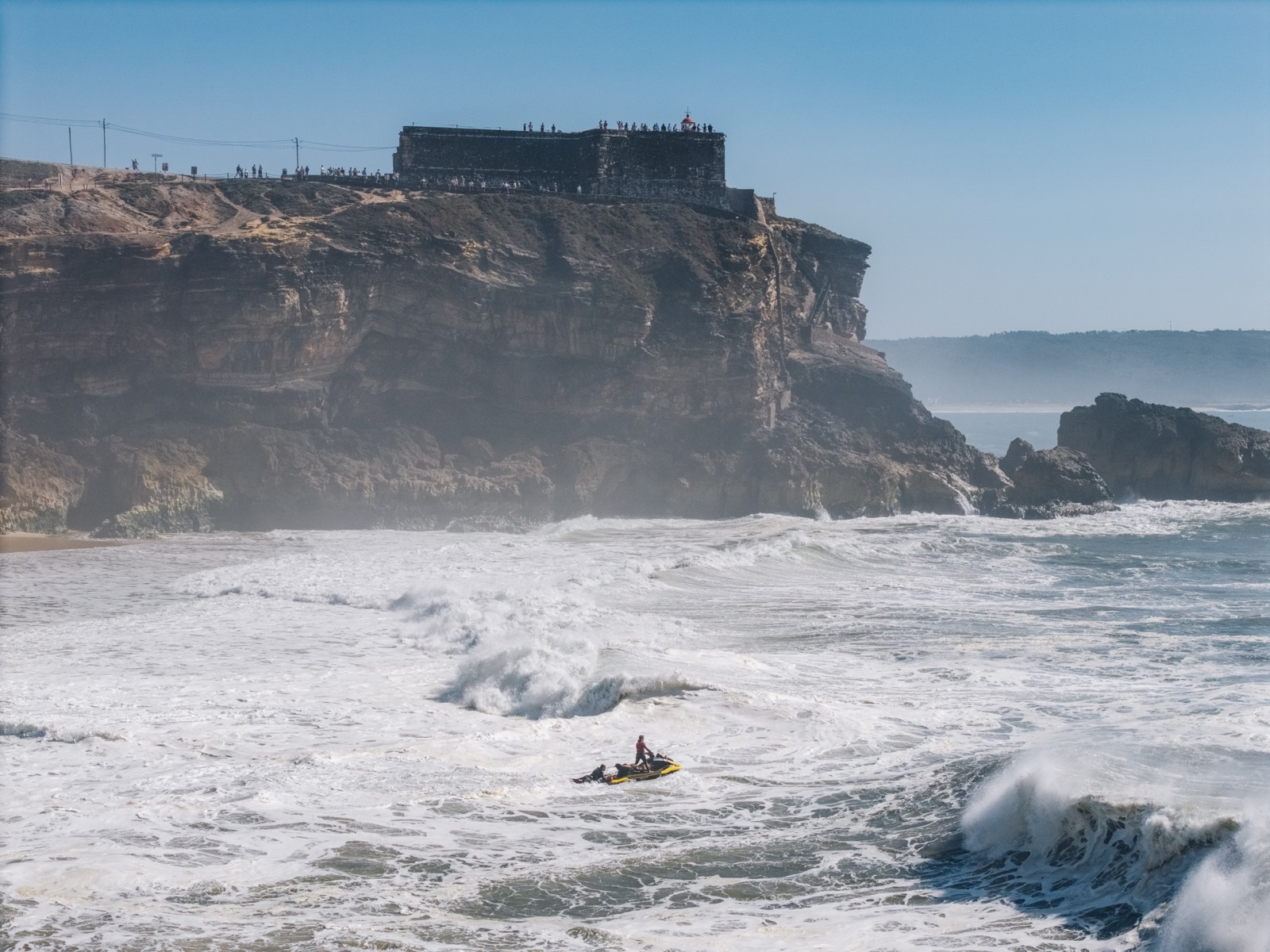 Huge winter surf exploding against dark cliffs